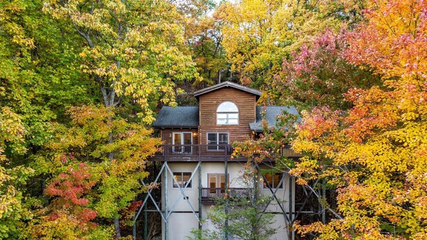 Ein zweistöckiges Holzhaus, umgeben von Herbstlaub.