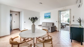 A spacious living area with a round table and chairs, a grey sofa, and a painting on the wall. - Villa Giulia: Views, Pool & Concierge by Feeling Italy (Sorrento)