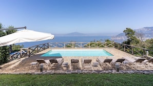 A rectangular pool with lounge chairs and a white umbrella, overlooking a scenic coastline. - Villa Giulia: Views, Pool & Concierge by Feeling Italy (Sorrento)