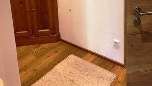 A hallway with a wooden cabinet, a framed landscape painting, and a beige rug on the floor.