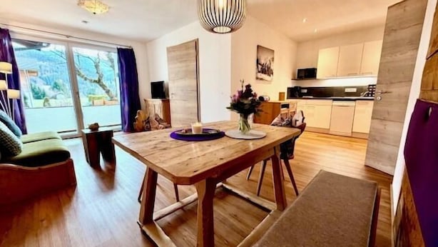 A modern kitchen with wooden cabinetry, a dining table, and a pendant light.