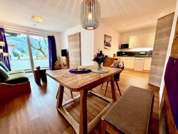 Une cuisine moderne avec des meubles en bois, une table à manger et un luminaire suspendu.