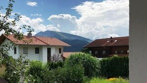A residential area with two houses, a garden with various plants, and a mountain in the background.