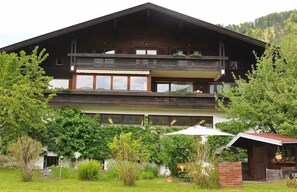 Situated amidst lush greenery, this chalet features a spacious balcony and large windows.