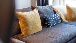 A grey sofa with multiple cushions in various patterns and colors. - Walker Suite No82 - Donnini Apartments (Kilmarnock)