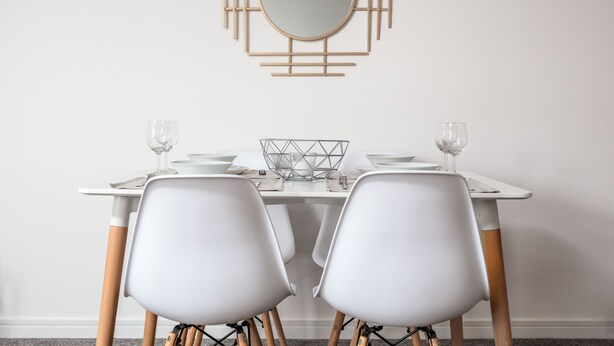 A dining table with two white chairs, a round mirror, and a geometric wall decoration. - Walker Suite No82 - Donnini Apartments (Kilmarnock)