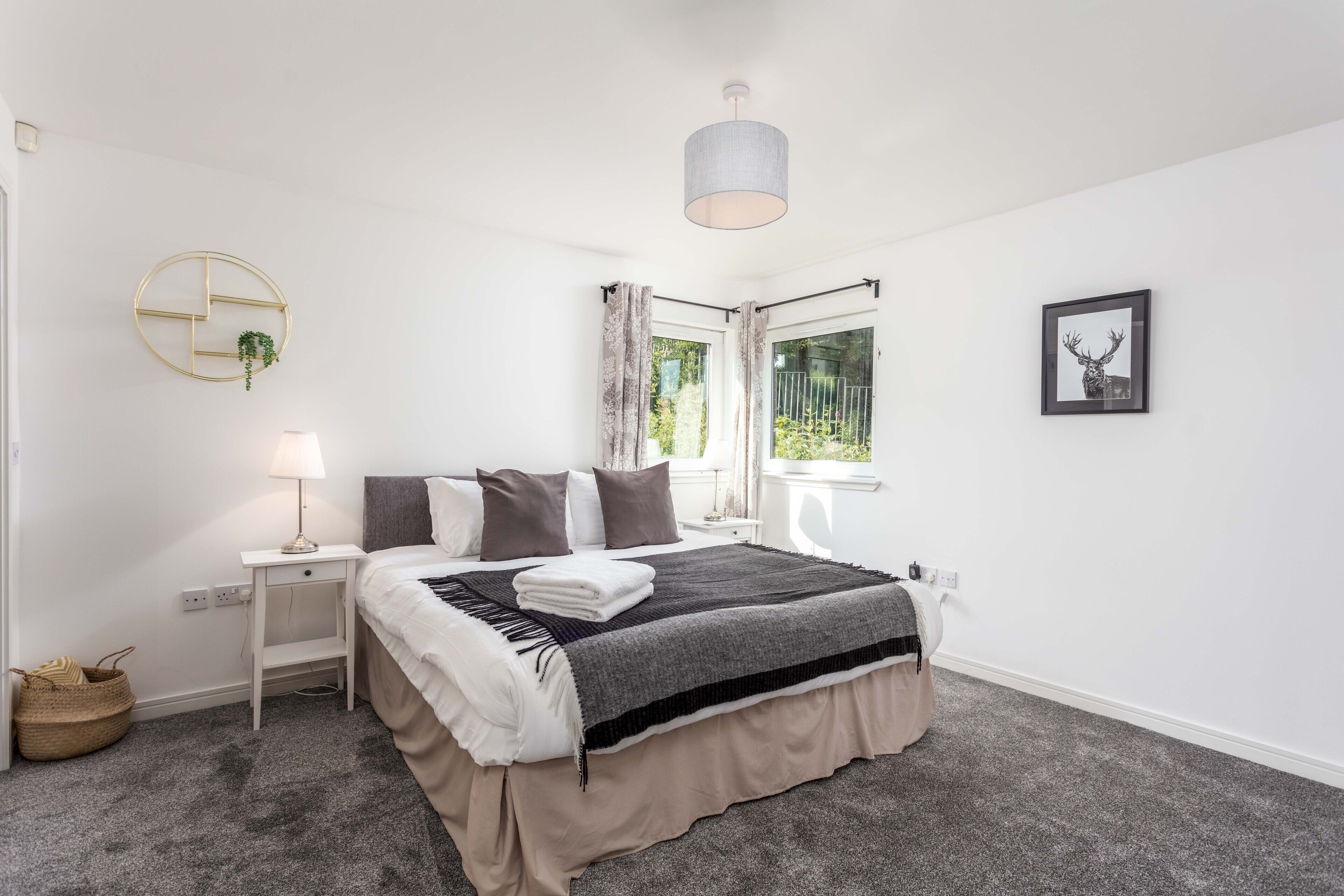 A bedroom with a bed, bedside table, lamp, and a window with curtains.