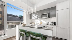 A modern kitchen with a large island, bar stools, a microwave, and a refrigerator. - reStays Ottawa (Ottawa)
