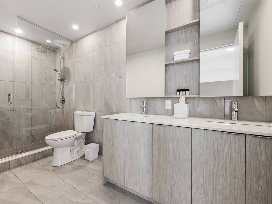 Uma casa de banho moderna com chuveiro, sanita e lavatório.