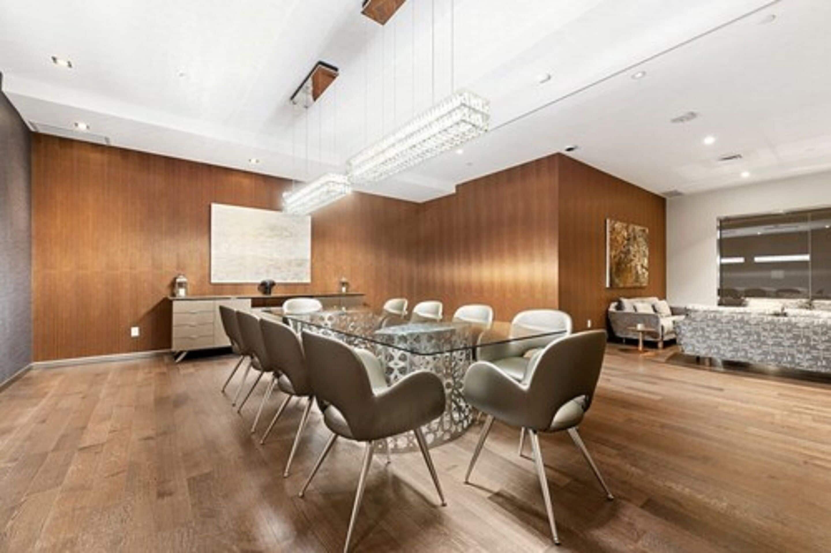 Une salle de conférence moderne équipée d’une table ronde en verre, de six chaises et d’un tableau blanc.