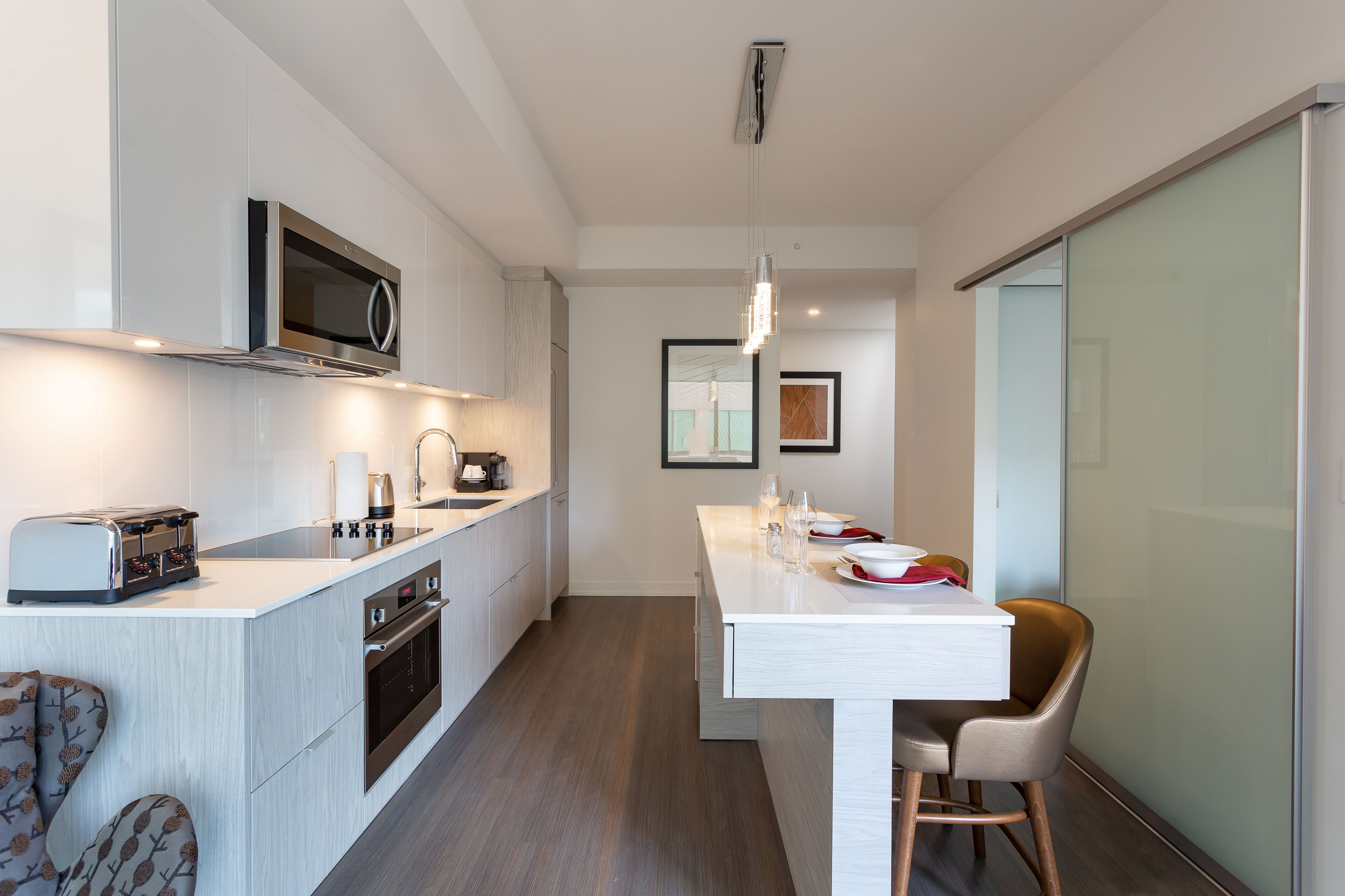 A modern kitchen with a microwave, toaster, and oven. There is a dining area with a table and chairs.