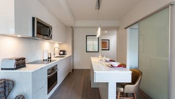 A modern kitchen with a microwave, toaster, and oven. There is a dining area with a table and chairs.