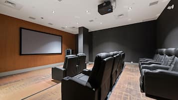 A modern cinema room with a large screen, reclining seats, and a carpeted floor.