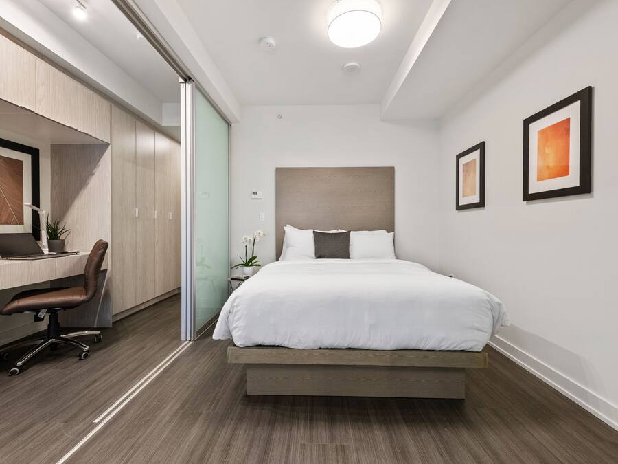 Una habitación de hotel moderna con una cama, escritorio, silla y dos cuadros en la pared.