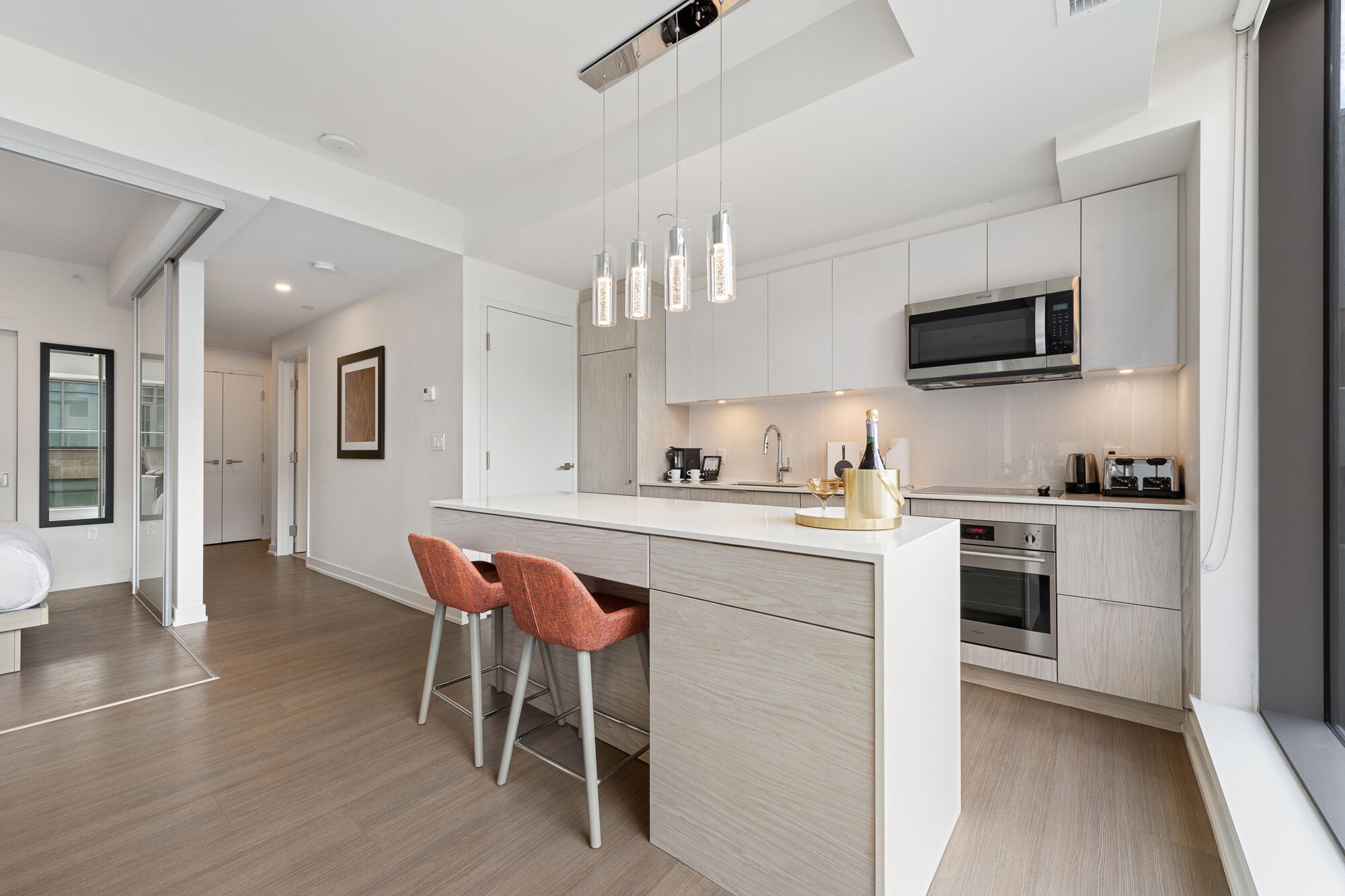 A modern kitchen with a central island, bar stools, a microwave, and a toaster.