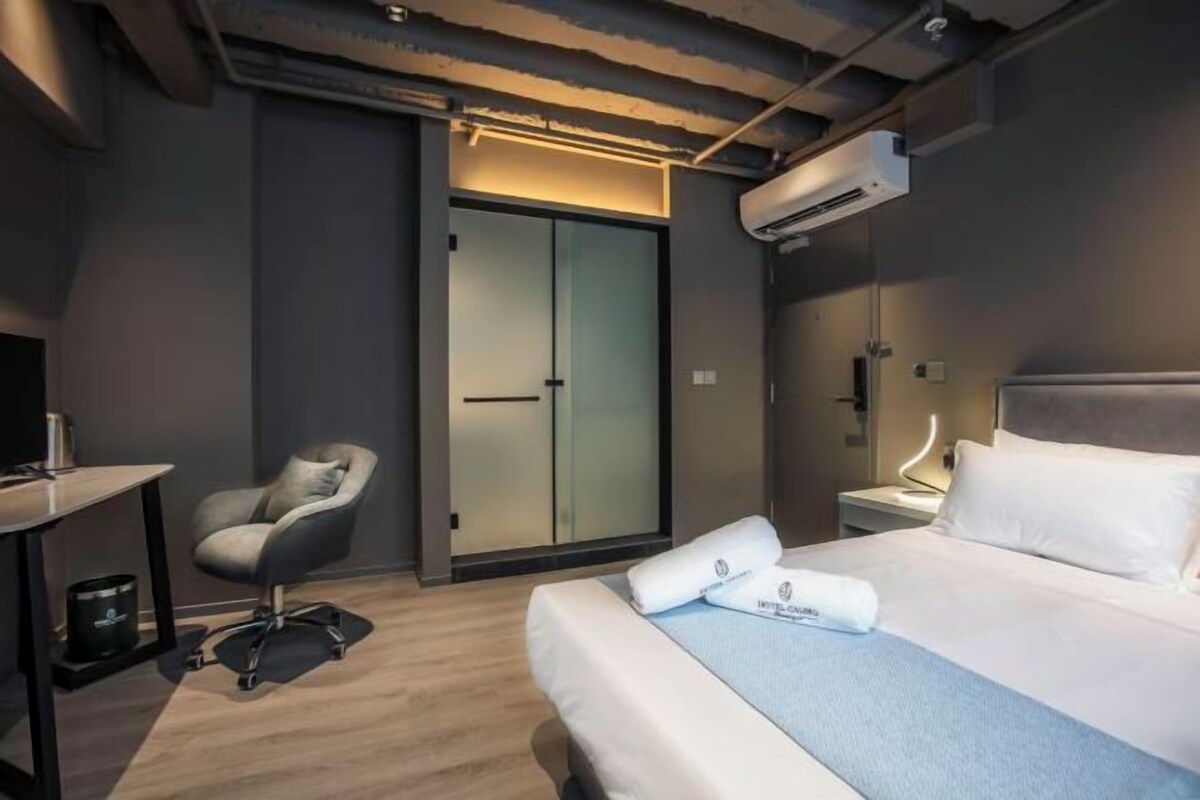 Una habitación de hotel moderna con una cama, un escritorio, una silla y un equipo de aire acondicionado.