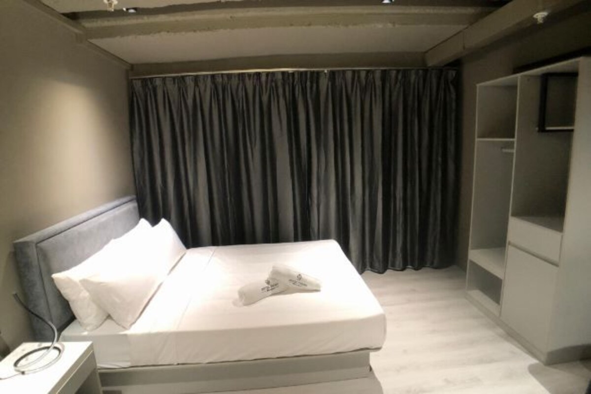 Une chambre d’hôtel moderne avec un lit bien fait, une table de chevet avec un téléphone et une étagère intégrée pour la télévision.