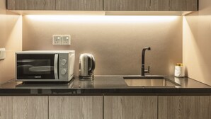 Una cocina moderna con microondas integrado, hervidor y pileta.