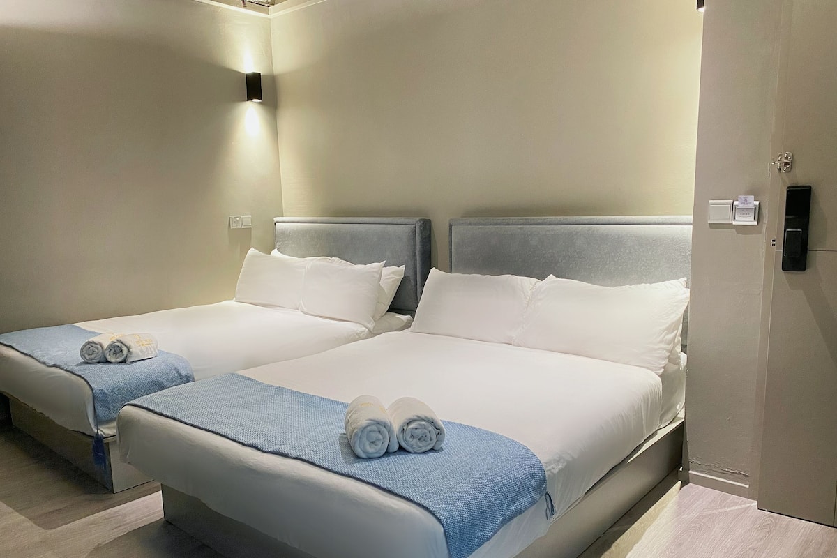 Two single beds with white linens and blue blankets, each with rolled towels.