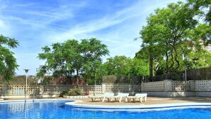 A swimming pool with lounge chairs and a fence. - Quiet apartment near the sea (Salou)