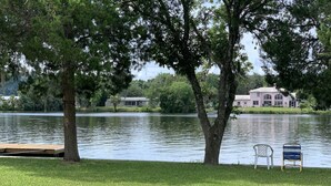 A lakeside view with a grassy area, a dock, and a house in the background. - Beautiful Indian Lake with canal leading to Crystal River and the Ocean. (Crystal River)