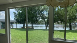 A room with large sliding glass doors leading to a grassy area with a lake and trees. - Beautiful Indian Lake with canal leading to Crystal River and the Ocean. (Crystal River)