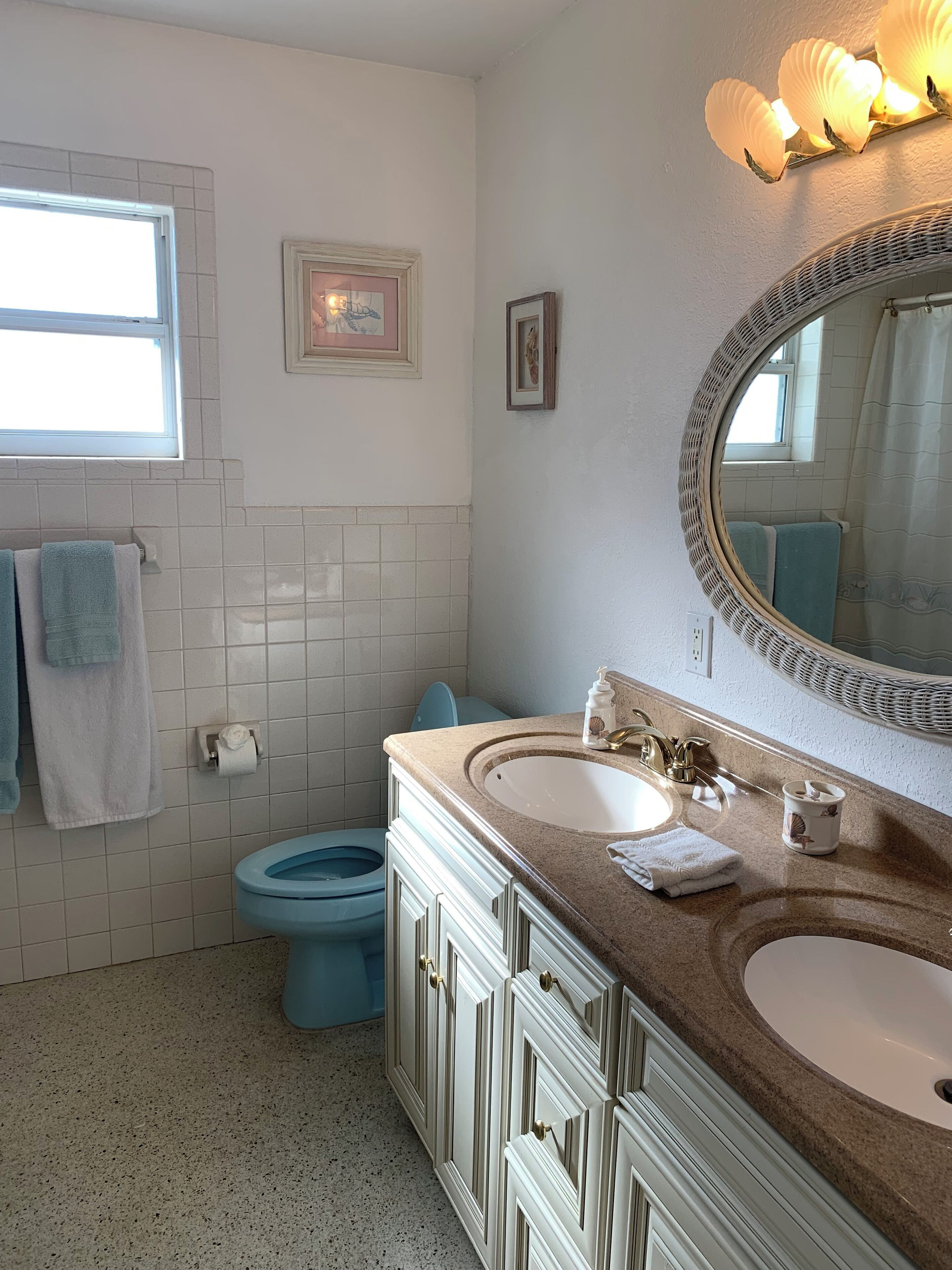 A bathroom with two sinks, a toilet, a window, and a mirror.