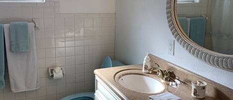 A bathroom with two sinks, a toilet, a window, and a mirror.