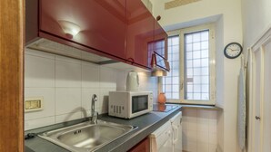 A compact kitchen with a stainless steel sink, a microwave, and white cabinets. - Fontanella Borghese (Rome)