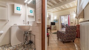 A bathroom with a sink, mirror, and two first aid signs. - Fontanella Borghese (Rome)