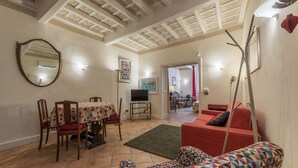 A living room with a dining area, a television, and a red sofa. - Fontanella Borghese (Rome)