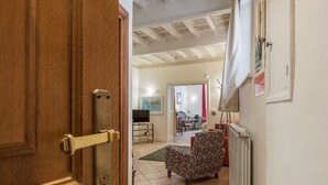 An open door leading to a living room with a patterned armchair, a television, and a dining area in the background. - Fontanella Borghese (Rome)