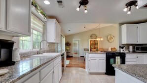 A modern kitchen with white cabinetry, granite countertops, and a central island. - Enchanting 3 BR, minutes from Winerys, Snow Sking, exhilarating Rafting Tours. (Medford)