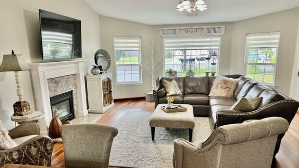 A living room with a fireplace, leather sofa, armchairs, and a television mounted above the fireplace. - Enchanting 3 BR, minutes from Winerys, Snow Sking, exhilarating Rafting Tours. (Medford)