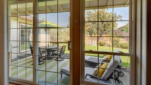 A sliding glass door leading to an outdoor patio with a table and chairs, a lawn, and a view of a house and trees. - Enchanting 3 BR, minutes from Winerys, Snow Sking, exhilarating Rafting Tours. (Medford)