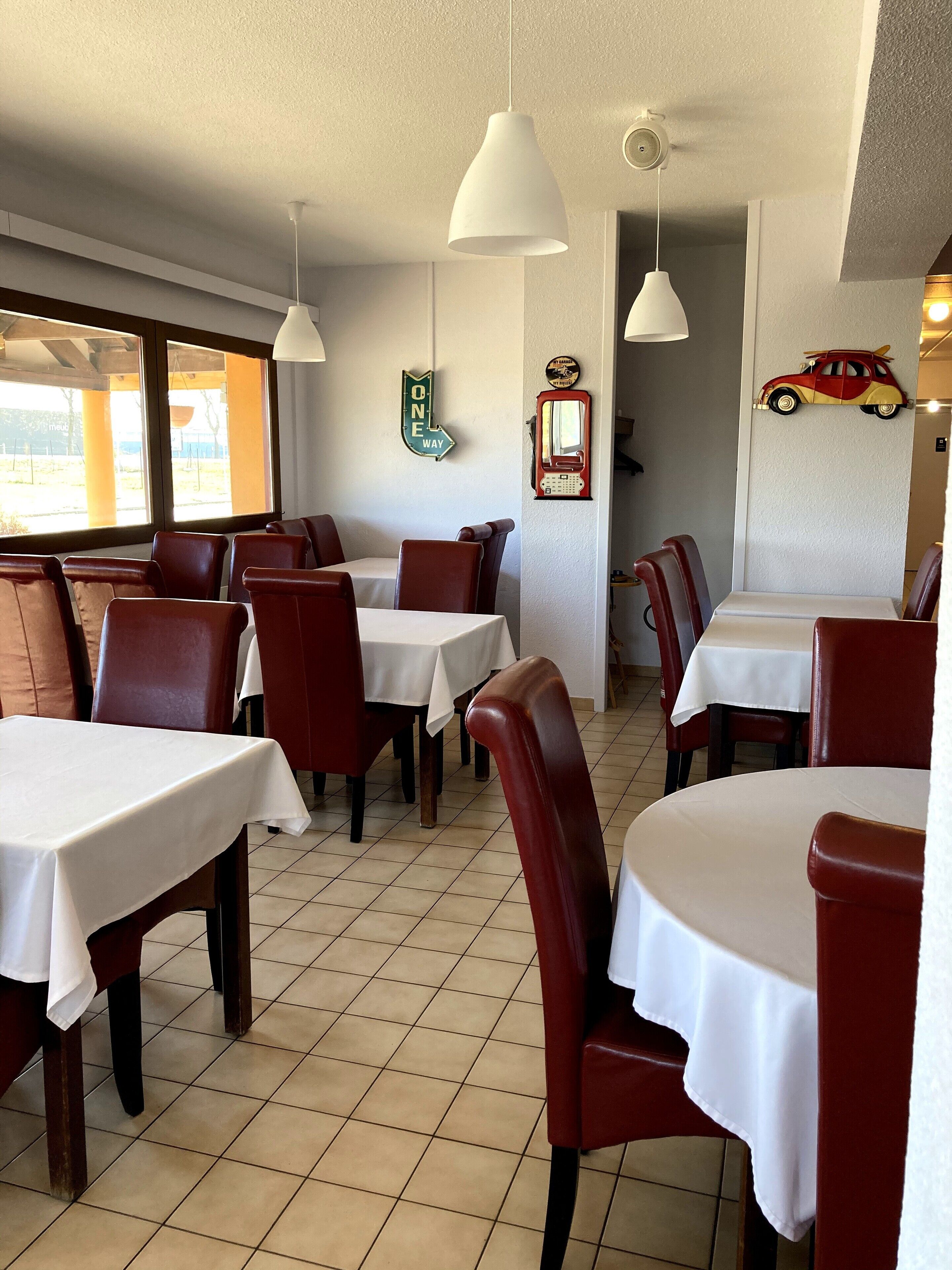 A restaurant interior with tables and chairs, a 'ONE WAY' sign, a vintage telephone, and a car decoration on the wall.