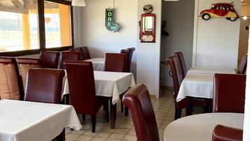 A restaurant interior with tables and chairs, a 'ONE WAY' sign, a vintage telephone, and a car decoration on the wall.