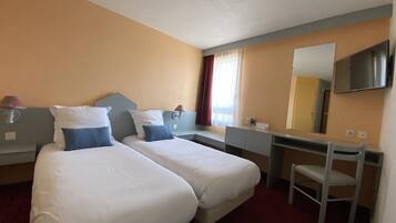 A hotel room with two beds, a desk, a chair, a mirror, and a window with curtains.