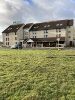 Um hotel BRIT HOTEL de vários andares, com telhado plano, área de estar ao ar livre coberta e estacionamento.