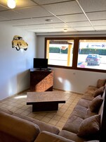 Uma sala de estar com sofá, mesa de centro, televisão e um enfeite de carro fixado na parede.