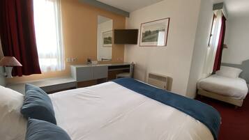 Hotelkamer met een groot bed, een bureau, een stoel, een televisie en een raam met gordijnen.
