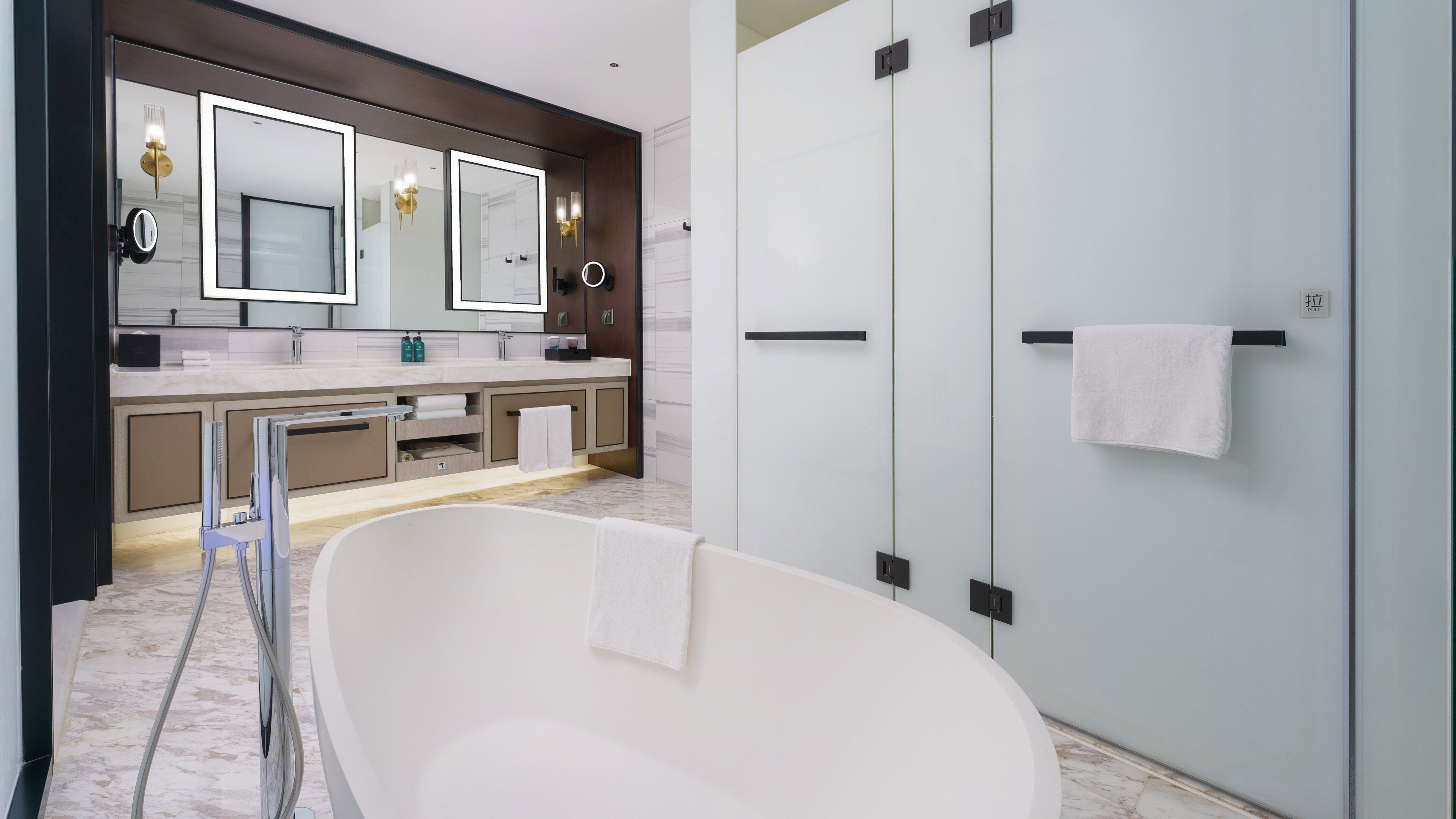 Un baño moderno con una bañera independiente, un espejo grande y un box de ducha de vidrio.