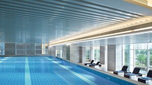 A large indoor swimming pool with clear blue tiles, a modern ceiling design, and lounge chairs by the windows. - Crowne Plaza Dalian Xinghai by IHG (Dalian)