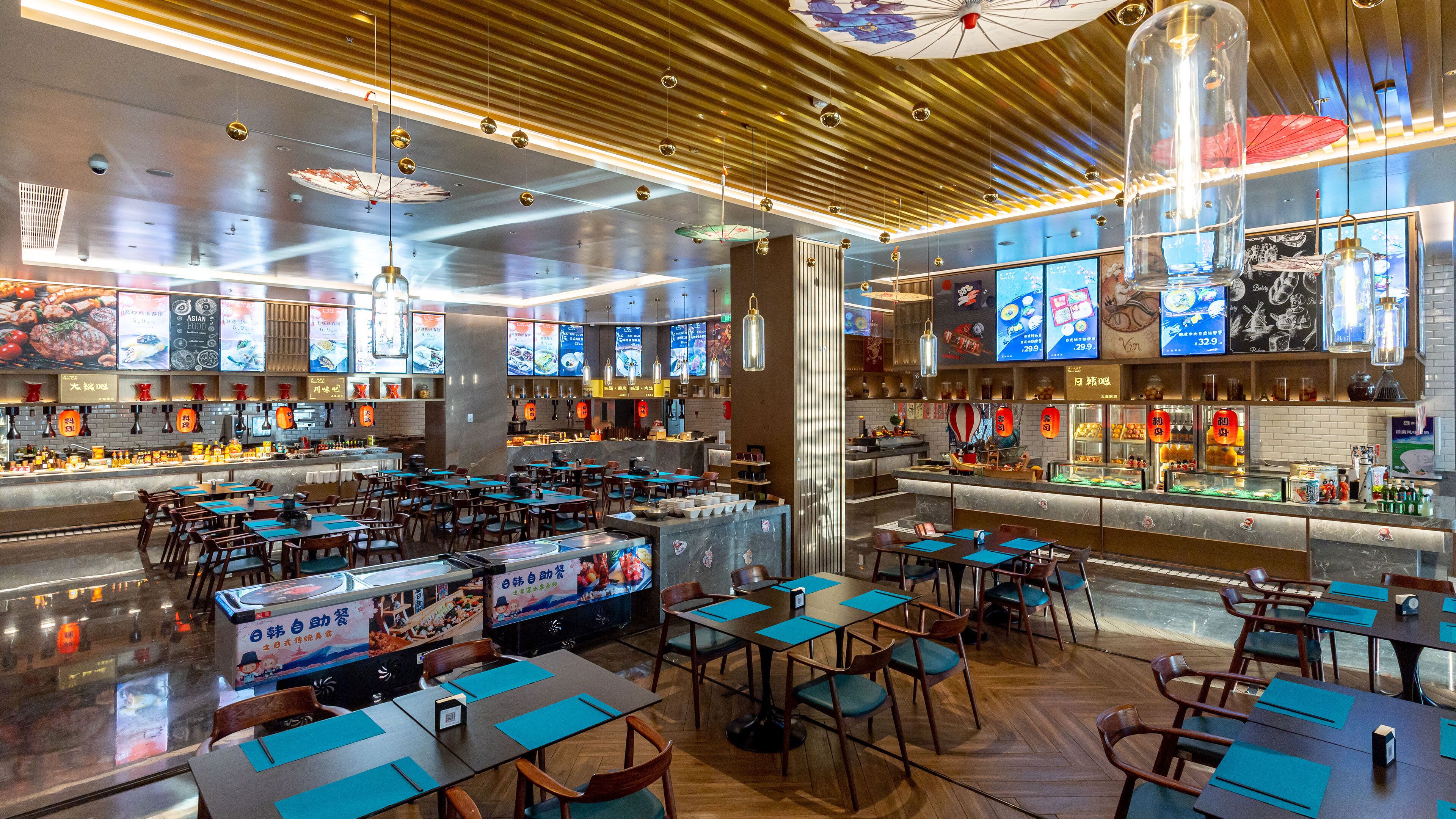 A modern restaurant interior with multiple dining tables and chairs, a bar area, and various food display cases.