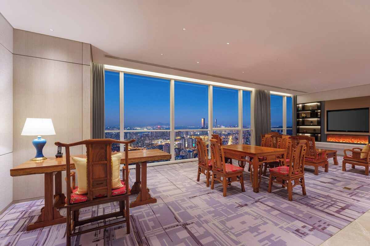 A spacious living room with a large city view, a fireplace, and a TV.