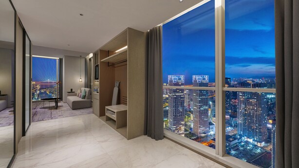 A modern hotel room with a large city view, a cozy seating area, and a minimalist design. - Crowne Plaza Dalian Xinghai by IHG (Dalian)