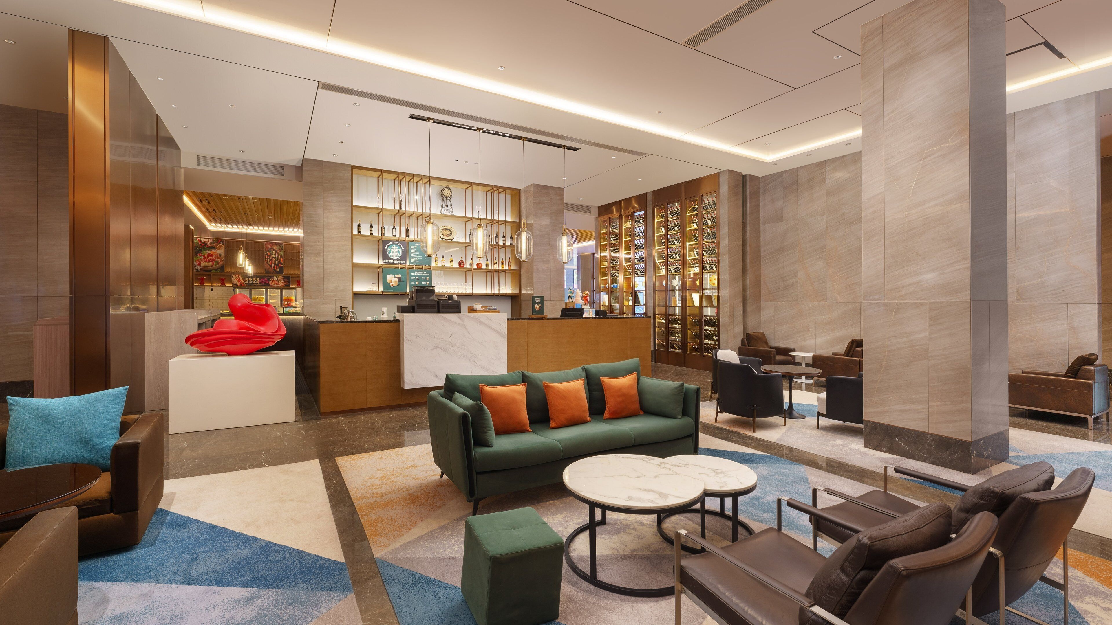 A modern lobby with a reception desk, seating area, and a wine display.