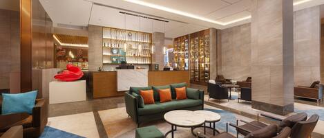 A modern lobby with a reception desk, seating area, and a wine display.
