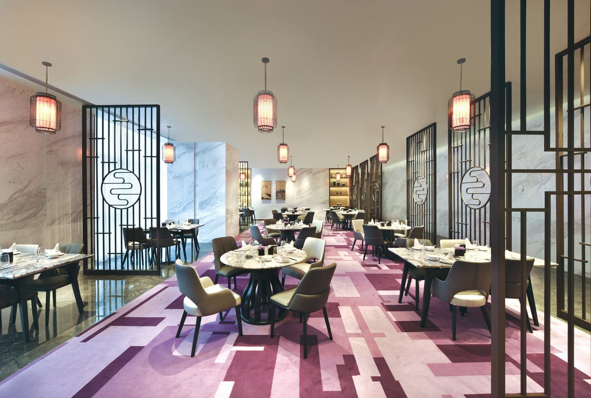 A modern dining area with round tables, chairs, and pendant lighting.