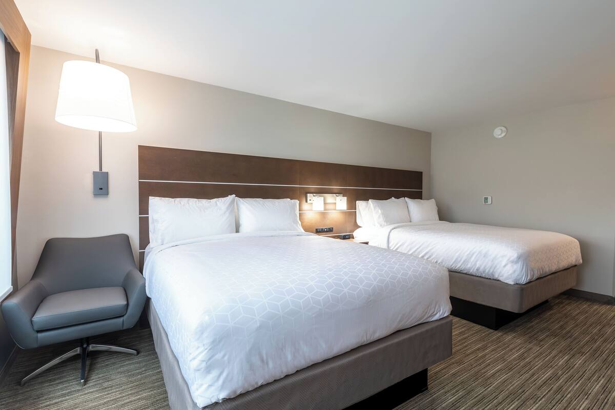 A hotel room with two beds, a desk, and a chair.